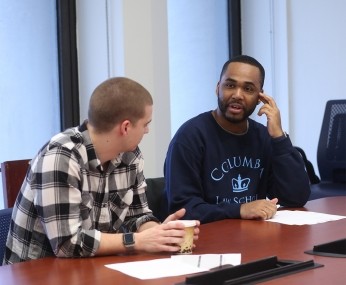 two men talking at a desk